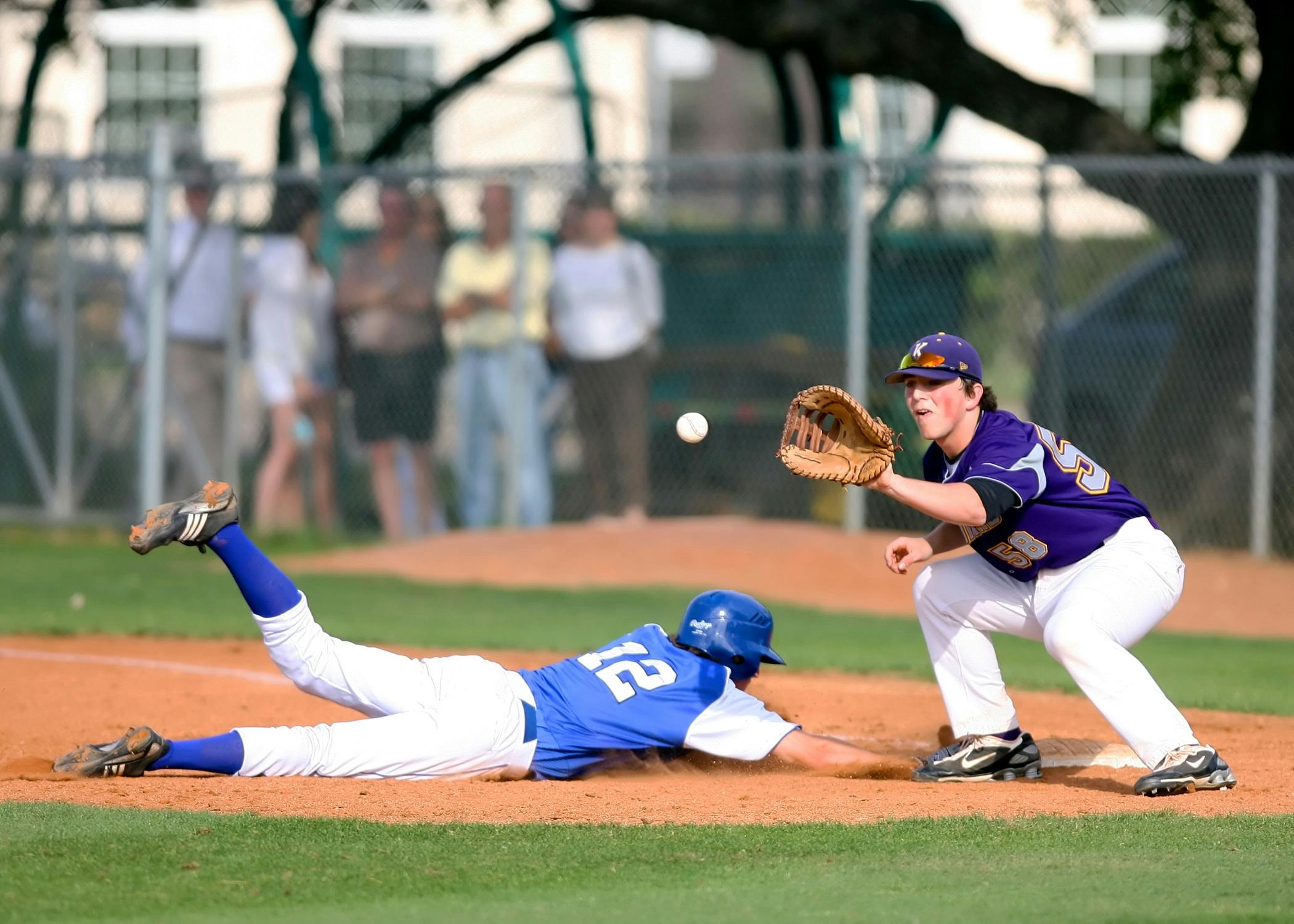 A thrilling moment in a baseball game as a runner slides into base while the fielder prepares to catch the ball.